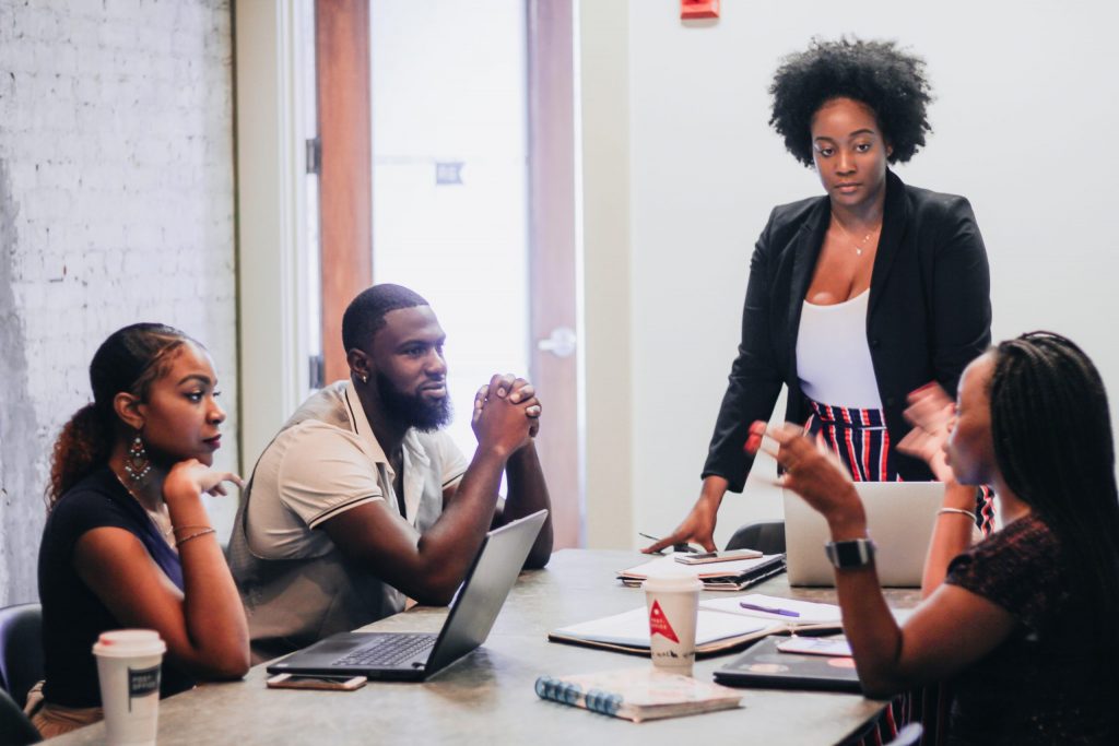 3 Black Women and 1 Black Man sitting at a table talking